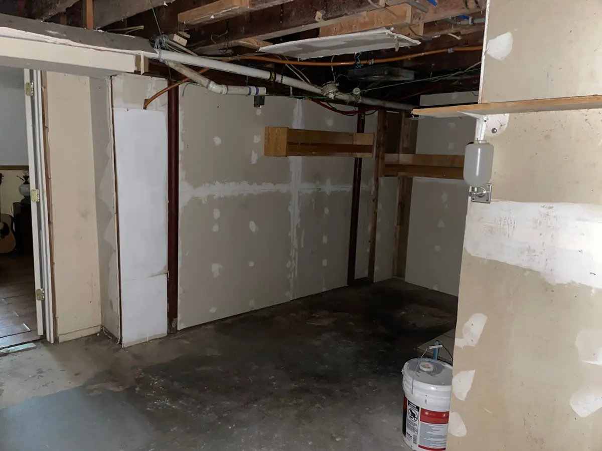 Wondering what your Shirley house is worth: basement with an open ceiling and patched drywall