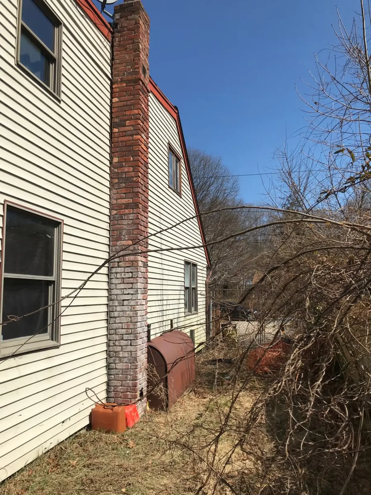 Selling a house with an oil tank in Shirley: rusted oil tank beside a brick chimney
